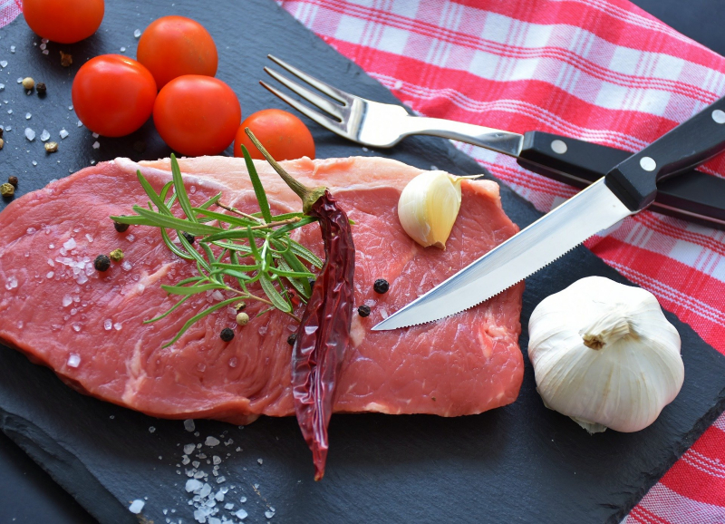 Rohes Stück Fleisch mit Besteck und Gewürzen. Rohes Stück Fleisch